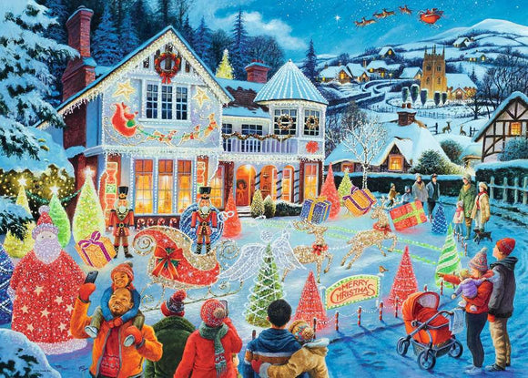 A festive jigsaw puzzle illustration titled 'The Christmas House' by Ravensburger. The scene features a charming house adorned with colorful Christmas lights, surrounded by joyful families, cheerful snowmen, and elegantly wrapped gifts. In the background, a snowy town scene with a starry sky and Santa's sleigh can be seen, creating a warm and inviting holiday atmosphere.
