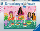 A colorful Ravensburger jigsaw puzzle featuring a ladies' brunch scene. Four women dressed in vibrant outfits enjoy a table filled with food and drinks, surrounded by flowers and decorative tableware. The design is lively and beautifully illustrated, capturing a joyful gathering.