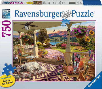 A vibrant jigsaw puzzle featuring a cozy front porch scene, adorned with a sleeping dog on a cushion, colorful flowers in hanging baskets, and scenic mountains in the background. The puzzle consists of 750 large pieces designed for easy handling and assembly.