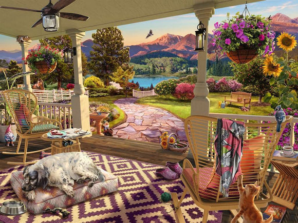 A picturesque front porch scene depicted in a large jigsaw puzzle by Ravensburger. The vibrant image features a cozy seating area with a dog resting on a pet bed, colorful potted plants, and a beautiful view of mountains and a lake in the background. A cat curiously observes from a nearby chair, while a decorative rug adds charm to the space. The overall atmosphere is tranquil and inviting, highlighting a serene outdoor living environment.