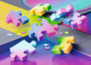 A colorful array of gradient puzzle pieces from the Karen Puzzles Gradient Cascade META Puzzle by Ravensburger, showcasing vibrant shades in pink, blue, green, and yellow. The pieces are displayed against a geometric background, emphasizing their translucent, modern design, ideal for puzzle enthusiasts.