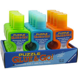 A display of Puzzle Glue & Go! by Ravensburger, featuring a set of colorful glue bottles in green, blue, and orange. The product is designed to permanently seal 2 jigsaw puzzles with up to 1000 pieces each, making it ideal for puzzle enthusiasts who want to preserve their completed artworks.