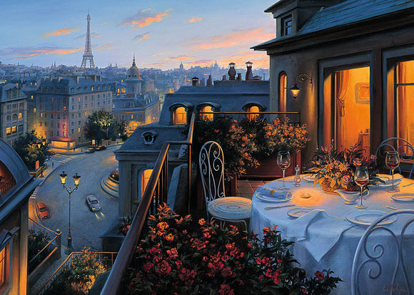 A beautifully illustrated jigsaw puzzle titled 'Paris Balcony' by Ravensburger, featuring a serene evening scene from a balcony overlooking the city of Paris. The image displays a picturesque view with the Eiffel Tower in the background, a table set for dinner adorned with flowers and wine glasses, and the enchanting glow of city lights illuminating the quaint streets below.