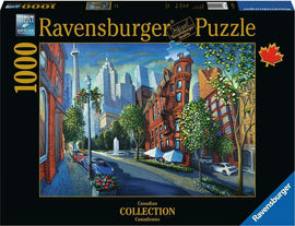 The Flat Iron jigsaw puzzle by Ravensburger features a vibrant urban scene with tall buildings, a fountain, and lush greenery. The packaging displays a picturesque view of city architecture and a cobblestone street.