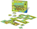 Rivers Roads and Rails game by Ravensburger featuring colorful path-building elements with roads, railroads, and rivers on vibrant gameplay tiles, alongside the game box displaying cheerful graphics.