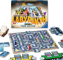 The Labyrinth Team Edition game by Ravensburger. The box is displayed at the back, with the game board featuring a maze filled with colorful paths and various pieces including game tokens in green, red, yellow, and purple. Additional cards and tiles are positioned around the board, showcasing the interactive gameplay elements. Ideal for team play and strategic fun for ages 8 and up.