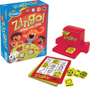 Zingo! game by ThinkFun features vibrant box art with children playing around a game board. The game includes a red Zingo! dispenser, a stack of yellow picture tiles, and a colorful game card filled with various images like animals, objects, and food, designed for 2 to 6 players ages 4 and up.