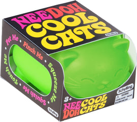 NeeDoh Cool Cats by Schylling is a vibrant green fidget toy shaped like a cute cat. The packaging features colorful text encouraging users to interact with the toy by squeezing, pinching, and touching it for stress relief and sensory fun.