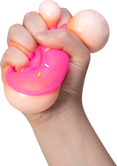 A hand squeezing a colorful NeeDoh Dohnuts stress ball from Schylling. The toy features a doughnut shape in pink with sprinkles, providing a satisfying sensory experience.