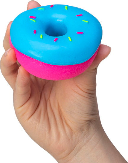 A person holding a colorful NeeDoh Dohnuts fidget toy shaped like a donut. The toy has a bright blue top with colorful sprinkles and a pink bottom.