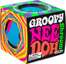 The Needoh Groovy Shroom by Schylling features a playful, colorful design with a bright blue and pink mushroom shape. The packaging showcases vibrant psychedelic patterns and bold text, highlighting that it’s a fun, stress-relieving fidget toy suitable for all ages. A warning label about small parts is included, indicating it's not for children under 3 years.