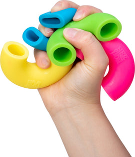 A person's hand gripping a colorful Needoh Mac 'N Squeeze fidget toy made by Schylling. The toy features four vibrant segments in yellow, green, blue, and pink, designed for sensory and stress relief.