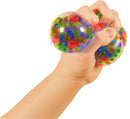 A hand squeezing a colorful, squishy stress ball filled with vibrant, shiny beads, designed to provide sensory stimulation and stress relief.
