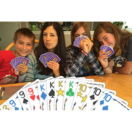 A group of four people enjoying a lively game of Five Crowns. They are sitting around a table, each holding playing cards. In the foreground, colorful cards with various symbols and numbers are visible, showcasing the game's vibrant design. Their expressions convey excitement and engagement, highlighting the fun atmosphere of game night.