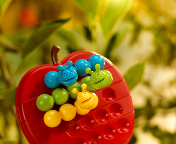 A colorful mechanical puzzle named Apple Twist from Smart Toys & Games. Features a bright red apple shape with various holes and six playful insect-like pieces in blue, green, yellow, and orange. The puzzle encourages problem-solving and fine motor skills for children.
