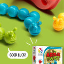 Apple Twist by Smart Toys & Games is a colorful mechanical puzzle featuring bright blue, green, and yellow caterpillar pieces. The puzzle box is displayed prominently, with a playful design and the tagline 'Good Luck!' indicating it’s a fun, brain-teasing game for one player. The background is vibrant green, enhancing the playful appeal of the product.