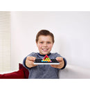 A young boy smiles while holding the IQ Puzzler Pro by SmartGames, showcasing colorful puzzle pieces arranged in a triangular formation on a black base. The background features a light-filled room with a bright window and a red sofa cushion.
