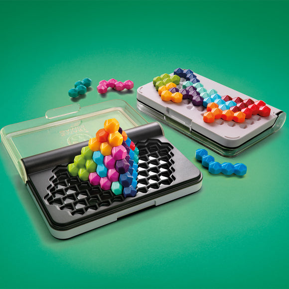 The IQ Six Pro by Smart Toys & Games is a colorful mechanical puzzle featuring various hexagonal pieces. The puzzle set includes a black base with a three-dimensional structure built from vibrant pieces in shades of pink, blue, green, and orange. The pieces are arranged to form two distinct patterns on the black and white bases, with additional scattered pieces around them, all presented on a bright green background.