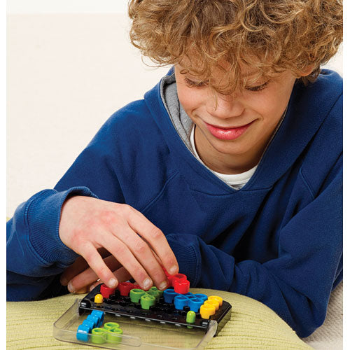 A young boy with curly hair is focused on solving the IQ Twist multi-level logic puzzle. He is placing colorful pieces onto a black puzzle board, showcasing concentration and enjoyment. The game features vibrant green, yellow, red, and blue pieces interlocked in a mechanical design, ideal for enhancing logical thinking skills.