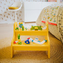 The Smartmax Roboflex Large set displayed on a stylish yellow shelf. It includes various colorful flexible components like tubes, connectors, and playful characters. The background features a patterned wall and a neat bed, creating a vibrant playroom atmosphere.