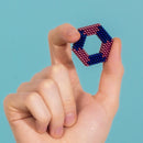 A person holding a colorful hexagonal puzzle made of magnetic balls in blue and pink hues. The puzzle is being showcased against a light blue background.