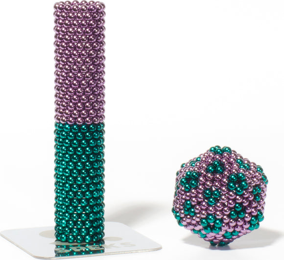 The Speks Stripes Nebula features a vibrant stacking and sculpting toy made from colorful magnetic beads. The image shows a tall column made of shiny teal and purple beads sitting on a reflective base, beside a smaller, spherical construction of the same beads, highlighting their versatility for creative play and stress relief.