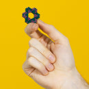 A person holding a vibrant, colorful fidget toy in the shape of a star, made of small magnetic beads. The toy is showcased against a bright yellow background, emphasizing its unique design and texture.