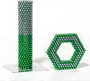 A colorful arrangement of magnetic balls forming a tall green and gray tower alongside a green and gray hexagonal structure. The product, Speks Stripes Third Rock by SPEKS, displays its vibrant colors and unique shapes, inviting creativity and imaginative play.