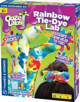 The Rainbow Tie-Dye Lab by Thames & Kosmos is a colorful DIY kit featuring a vibrant packaging design. The box showcases tie-dyed socks and scrunchies, along with bright dye bottles and images of science experiments. Perfect for ages 8 and up, it invites kids to explore dyeing and color mixing while creating their own stylish accessories.