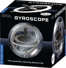 Thames & Kosmos Gyroscope in packaging. The gyroscope is enclosed in a transparent plastic sphere, showcasing its spinning mechanism in action. The box design features bold text highlighting 'Gyroscope' and the tagline 'The essential, spinning physics toy' along with the Thames & Kosmos branding.