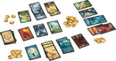 A vibrant tabletop setup for the Lost Cities Rivals card game by Thames & Kosmos. The image features several stacks of cards depicting various landscapes and treasures, gold tokens scattered throughout, showcasing the game's strategic elements and colorful artwork. Perfect for enthusiasts of tactical card games and fun-filled competition.