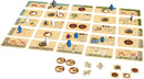 The board game Targi by Thames & Kosmos displayed with various game cards and player pieces scattered across a sandy terrain. The game features colorful meeples representing players and strategic elements for trade and resource management in a two-player setup. Each card depicts actions and resources related to game mechanics like raids and caravans, inviting strategic play.