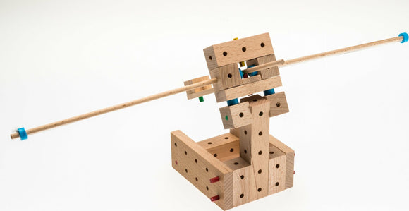 The Catapults Explorer DIY kit by Matador, featuring 56 wooden pieces designed for building a catapult. The assembly includes various colored pegs, showing intricate construction with precision fit. Ideal for hands-on learning and creative exploration.