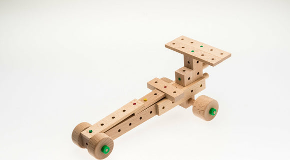 A wooden DIY kit from Matador featuring 50 pieces to create a racing car model. The kit showcases various blocks with holes and colored pegs, designed for imaginative play and construction.