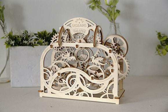 A beautifully crafted UGears 3D Theater DIY kit made of laser-cut wood. The intricate design features gears, patterns, and an ornate arch with the 'UGears Theater' engraving at the top. The model showcases an engaging mechanical aesthetic suitable for hobbyists and DIY enthusiasts.