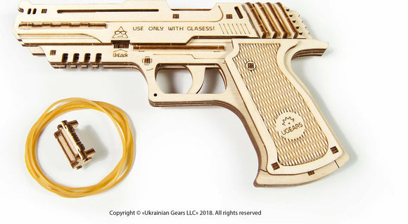 UGears 3D Wolf-01 Handgun DIY kit featuring intricately designed wooden parts, a rubber band, and an illustration urging use with glasses for safety. Ideal for DIY enthusiasts and model builders.