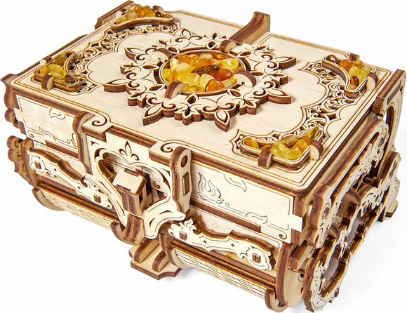 A detailed image of the UGears 3D Amber Box DIY kit, showcasing its intricate wooden design with ornate carvings and decorative amber-like beads on the top. The box features a charming, mechanical construction that invites creativity and hands-on assembly.
