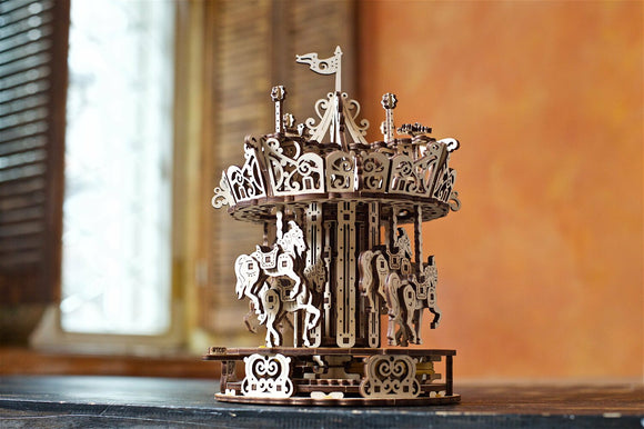 Ugears 3D Carousel model kit showcasing intricately designed wooden carousel with rotating horses. The elegant design features ornate decorations and a flag on top. It's perfect for DIY enthusiasts and collectors.