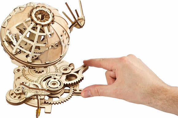 UGears 3D Globe DIY kit showcasing intricate wooden components and mechanical gears. A hand is interacting with the globe to demonstrate its functionality and craftsmanship.