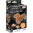 A 3D crystal jigsaw puzzle featuring a Dachshund in a vibrant amber color. The packaging shows the finished product alongside the puzzle pieces. Suitable for ages 12 and up, this puzzle has 41 pieces and is labeled as Level 1 difficulty.