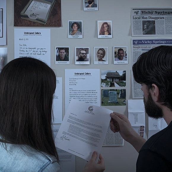 A couple of individuals closely examine a collection of documents and photographs pinned to a wall. The documents include letters and newspaper clippings related to Underwood Cellars. The individuals are engaged in a mystery game, analyzing clues to solve a puzzle. One person holds a letter while the other looks at the wall display, which features portraits and various texts connected to the game.