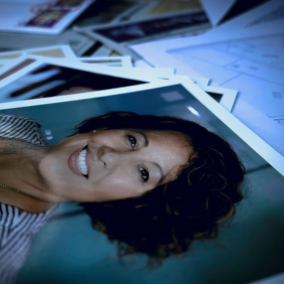 A collection of scattered photographs featuring a woman smiling, surrounded by various other images and papers, creating an artistic and candid composition.