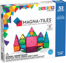 Magna Tiles Clear Colors 32 Piece Set, featuring colorful, translucent magnetic building tiles arranged to form a castle. The box showcases the product's educational focus on math, science, and creativity, perfect for ages 3 to 99.