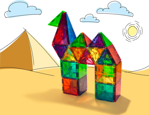 A vibrant 100-piece set of Magna Tiles in clear colors, arranged to create a colorful structure resembling a bird and a house. The tiles are geometric shapes, showcasing bright hues of green, red, blue, and yellow, set against a simple backdrop illustrating a desert with pyramids and a sun, emphasizing the creativity and educational potential of this DIY kit.