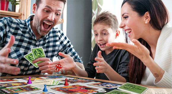 A family enjoying a game of Clue by Winning Moves. The scene shows a man and woman smiling and excitedly playing along with a young boy. Colorful game pieces and cards are visible on the table, creating a lively and engaging atmosphere.